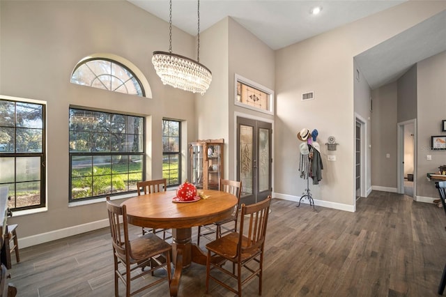 dining area featuring a wealth of natural light, a towering ceiling, and dark wood-type flooring