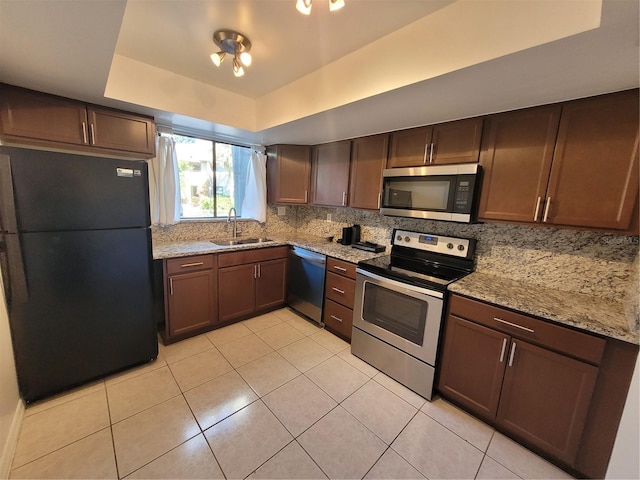 kitchen featuring tasteful backsplash, light stone countertops, sink, and stainless steel appliances