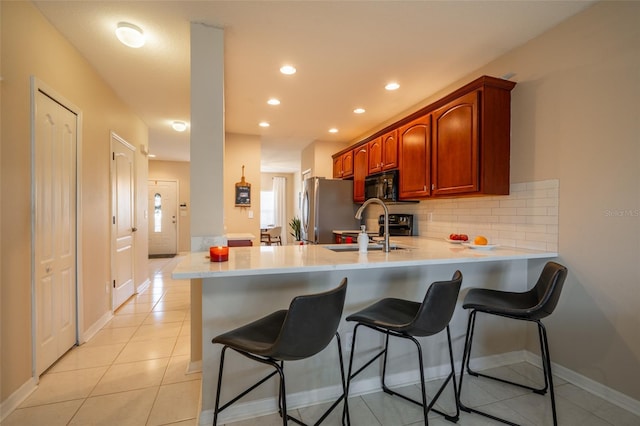 kitchen featuring backsplash, sink, stainless steel fridge, light tile patterned flooring, and kitchen peninsula