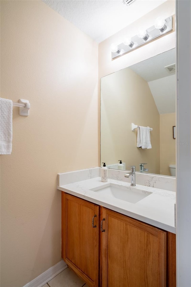 bathroom with a textured ceiling, vanity, lofted ceiling, and toilet