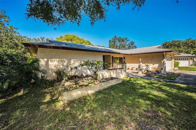 view of front facade with a garage, a front yard, and stucco siding