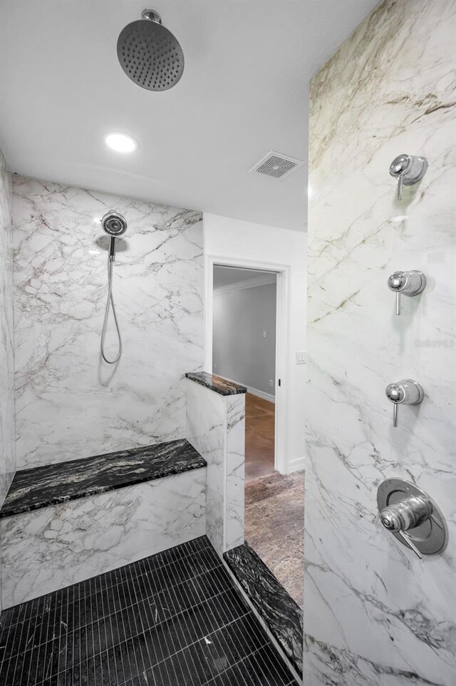 bathroom with a marble finish shower and visible vents