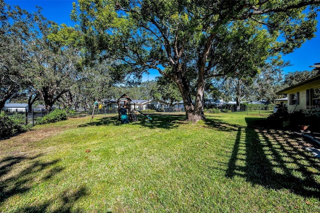 view of yard featuring playground community and fence