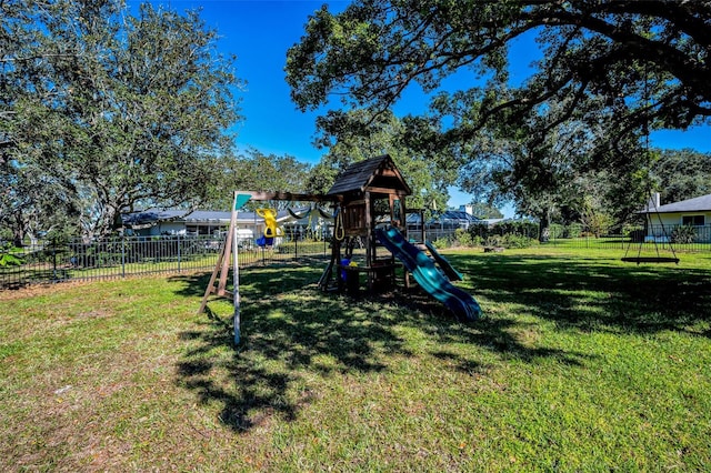 communal playground featuring a yard and fence