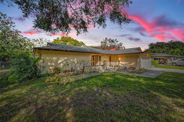 ranch-style home featuring a front yard, fence, and stucco siding