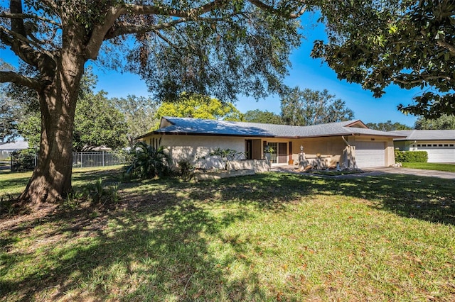 ranch-style house featuring an attached garage, a front yard, fence, and stucco siding