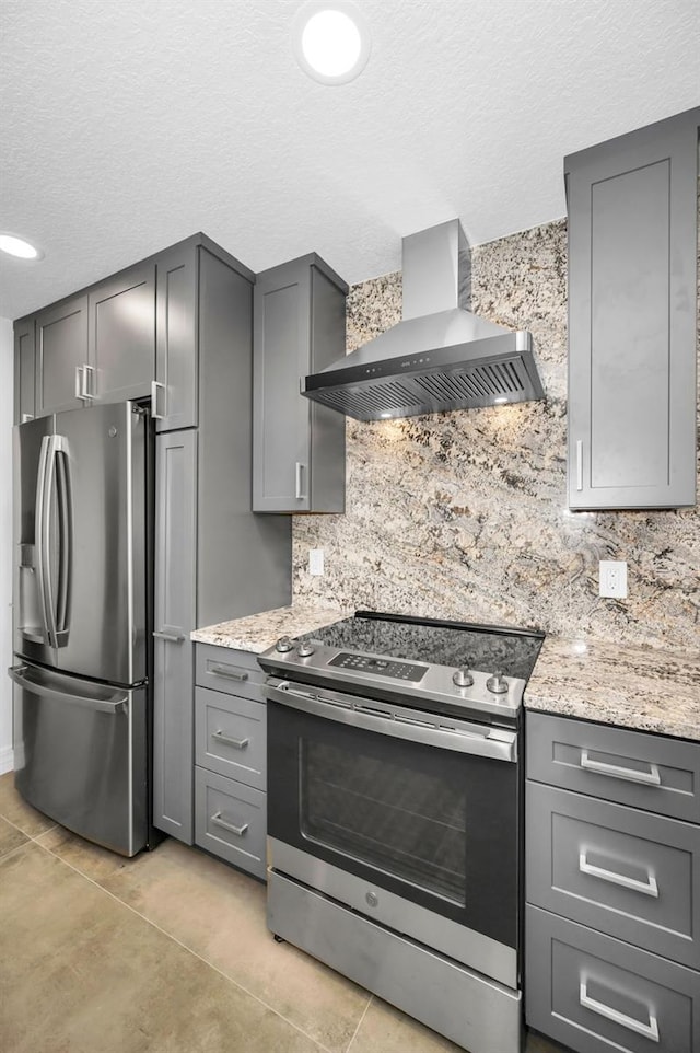 kitchen featuring tasteful backsplash, wall chimney exhaust hood, stainless steel appliances, and gray cabinetry