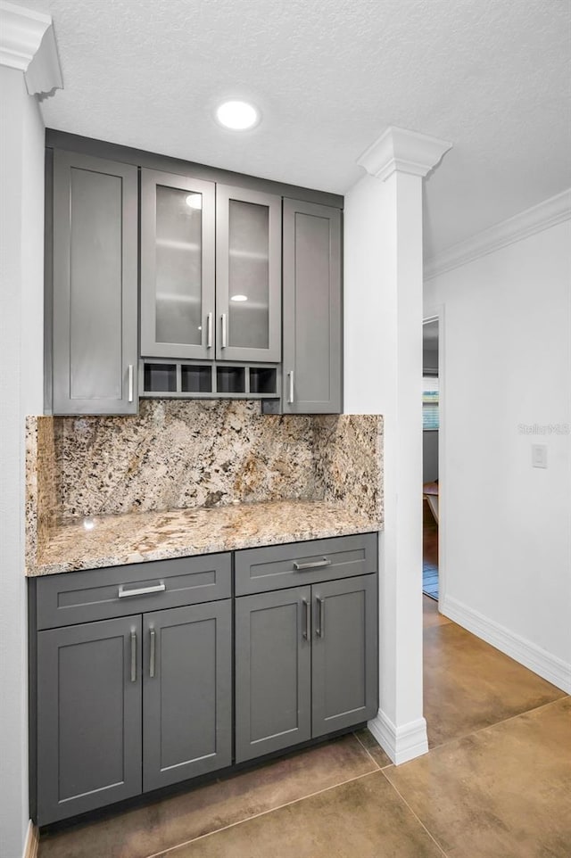 bar with ornate columns, baseboards, decorative backsplash, and ornamental molding