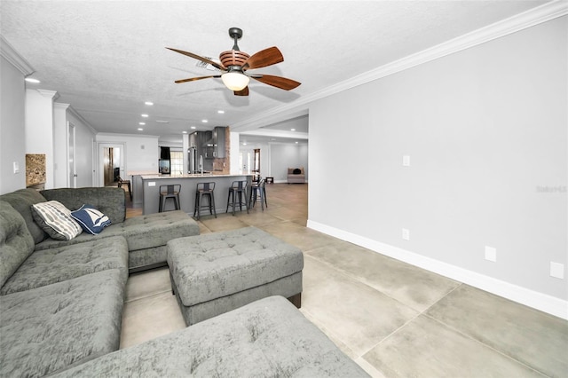 living area featuring a textured ceiling, recessed lighting, a ceiling fan, baseboards, and crown molding