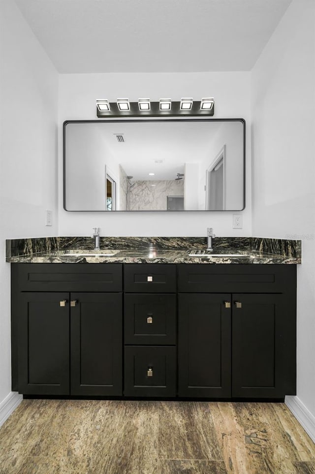 full bath with double vanity, a sink, and baseboards