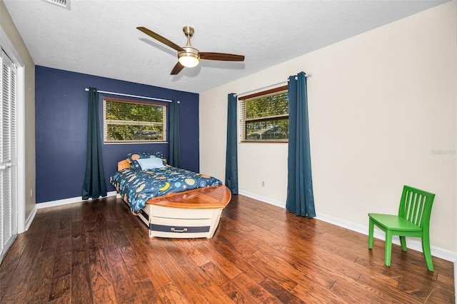 bedroom featuring a textured ceiling, baseboards, and wood finished floors