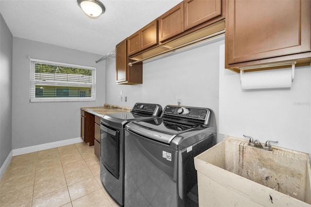 washroom with light tile patterned floors, a sink, baseboards, cabinet space, and washing machine and clothes dryer