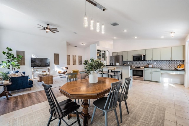 tiled dining space with ceiling fan and lofted ceiling