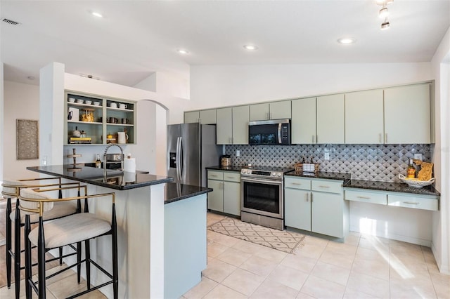 kitchen with tasteful backsplash, kitchen peninsula, appliances with stainless steel finishes, and vaulted ceiling