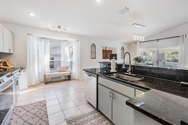 kitchen featuring white cabinetry, sink, stainless steel appliances, dark stone countertops, and pendant lighting