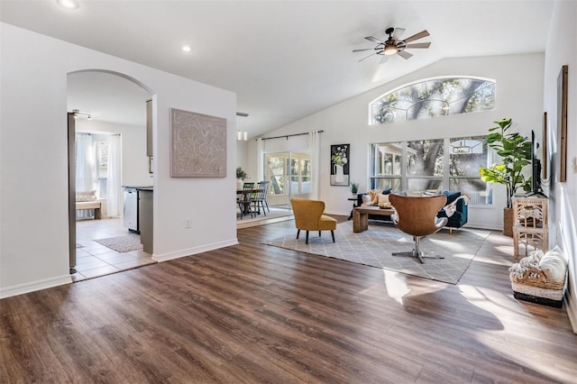 living area with ceiling fan, arched walkways, baseboards, wood finished floors, and lofted ceiling