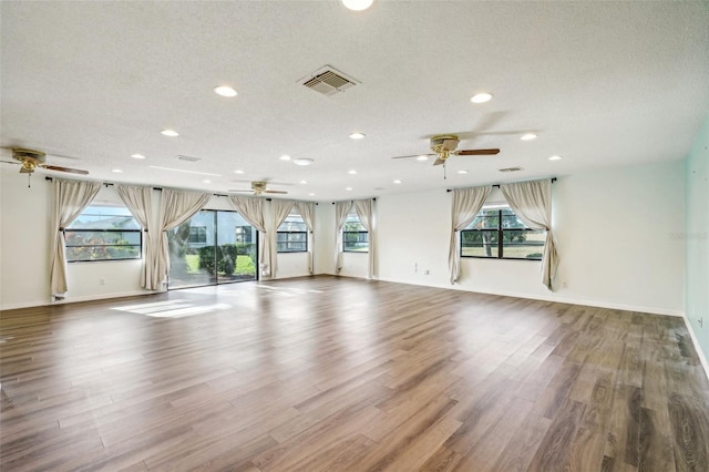 unfurnished living room featuring a healthy amount of sunlight, a textured ceiling, and wood-type flooring