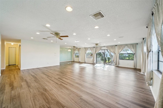 unfurnished living room featuring ceiling fan, light hardwood / wood-style floors, and a textured ceiling