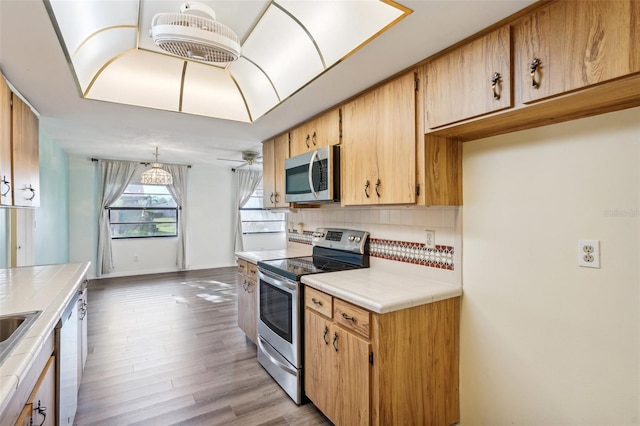 kitchen featuring pendant lighting, tile counters, light hardwood / wood-style floors, and appliances with stainless steel finishes