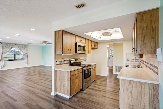 kitchen with hardwood / wood-style floors, backsplash, sink, and appliances with stainless steel finishes