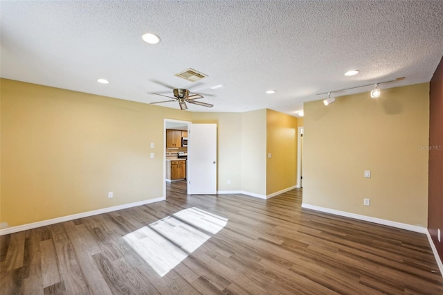 empty room with ceiling fan, track lighting, wood-type flooring, and a textured ceiling