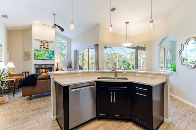 kitchen featuring dishwasher, an island with sink, light hardwood / wood-style flooring, and sink