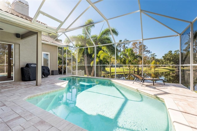 view of swimming pool with a patio area, a water view, and glass enclosure