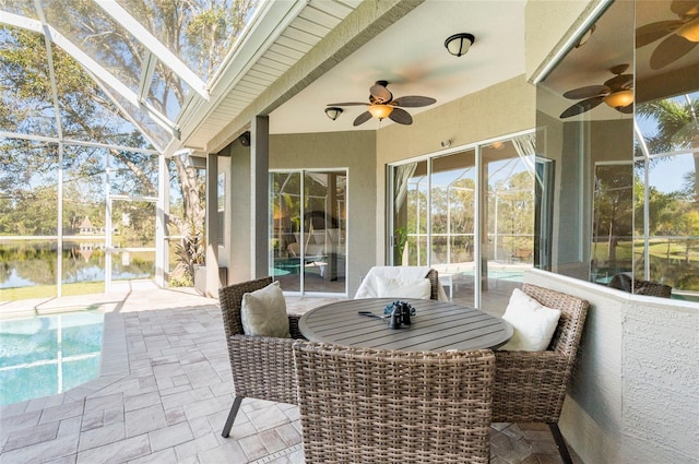 view of patio / terrace with a lanai, ceiling fan, and a water view