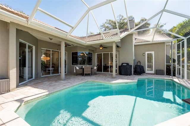 view of swimming pool featuring glass enclosure, ceiling fan, and a patio