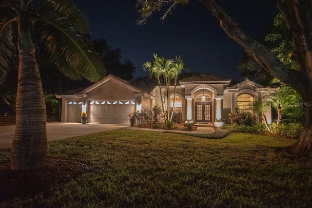 view of front of property featuring a lawn, a garage, and french doors