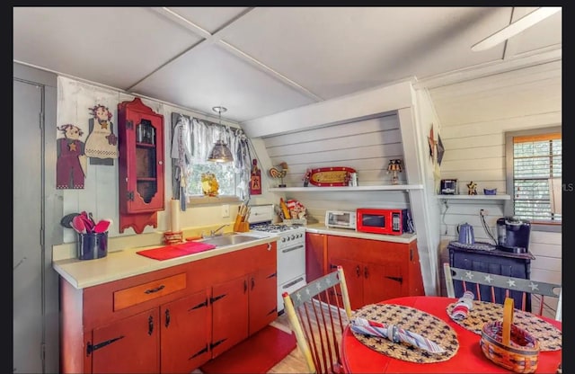 kitchen featuring pendant lighting, wood walls, lofted ceiling, sink, and white gas stove