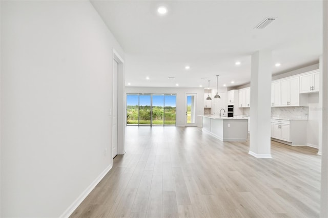 unfurnished living room with light wood-type flooring and sink