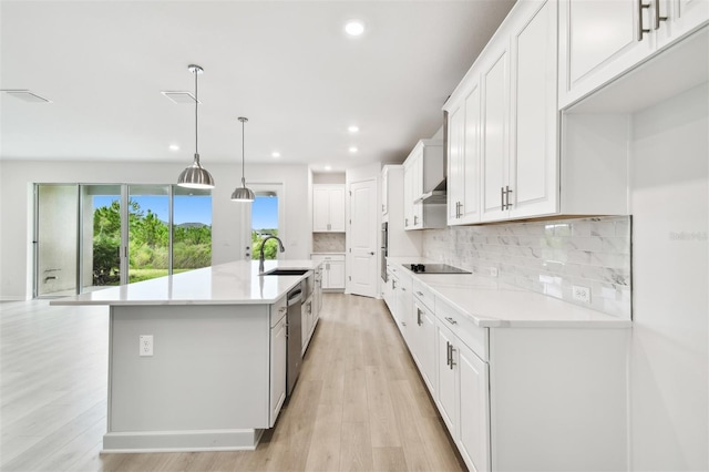 kitchen with white cabinetry, hanging light fixtures, light hardwood / wood-style flooring, an island with sink, and black electric cooktop