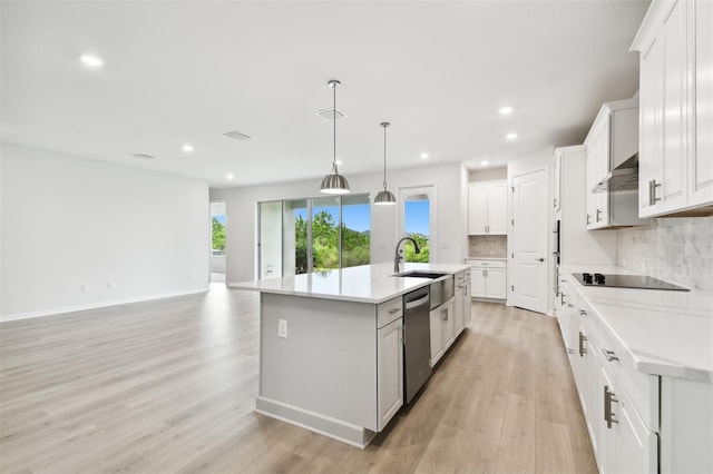 kitchen with white cabinets, sink, light hardwood / wood-style flooring, stainless steel dishwasher, and an island with sink