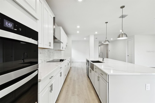 kitchen with pendant lighting, a center island, white cabinets, sink, and light hardwood / wood-style floors