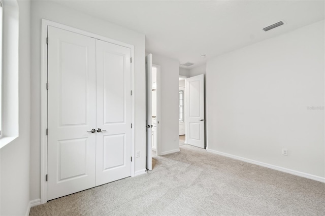 unfurnished bedroom with light carpet and a closet