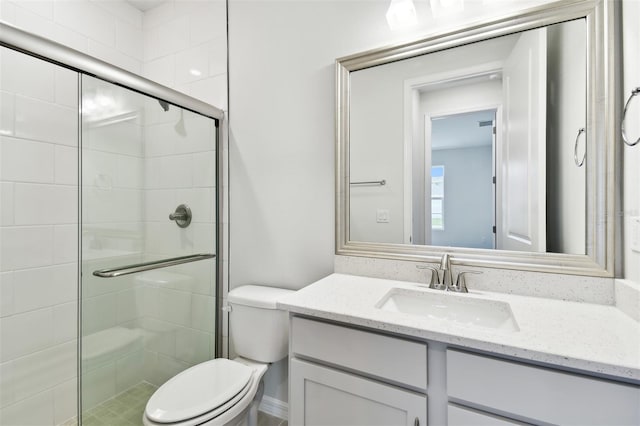 bathroom featuring toilet, vanity, and walk in shower