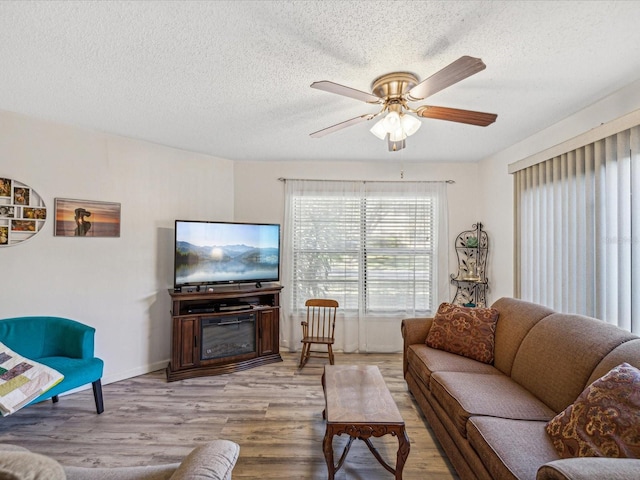 living room with ceiling fan, light hardwood / wood-style floors, and a textured ceiling