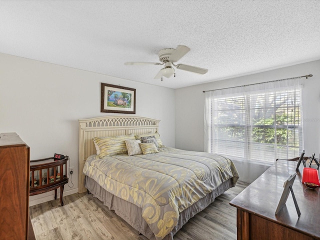 bedroom with a textured ceiling, light wood-type flooring, and ceiling fan