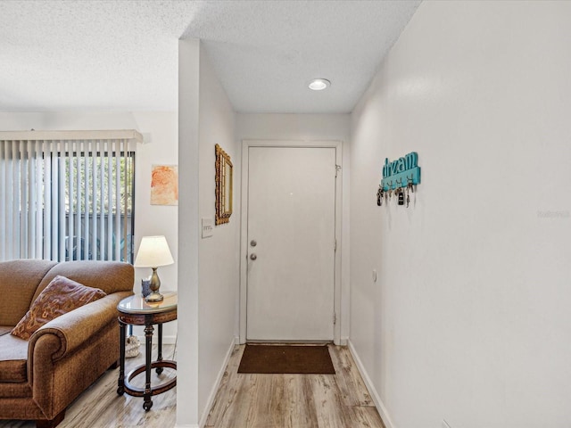 doorway featuring light wood-type flooring and a textured ceiling