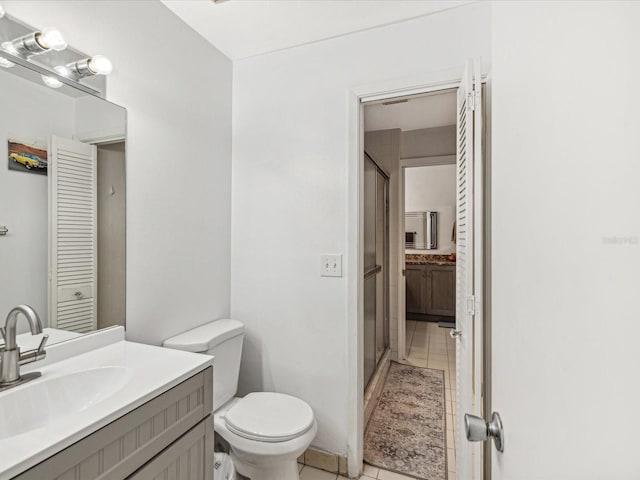 bathroom featuring toilet, vanity, tile patterned floors, and a shower with shower door