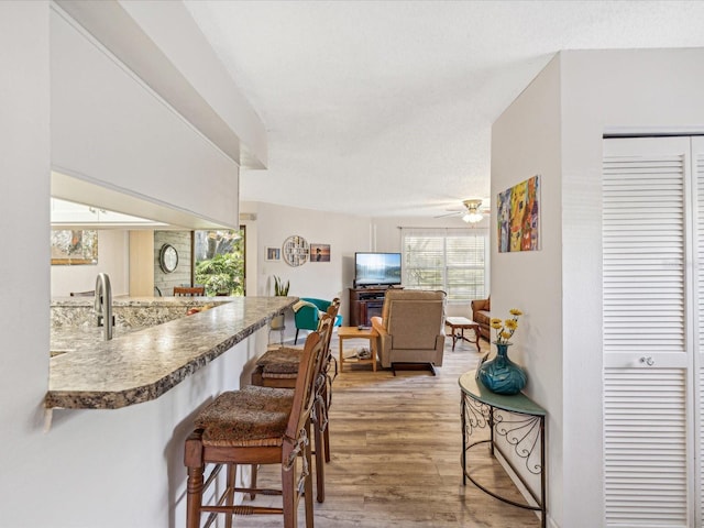 kitchen featuring ceiling fan, wood-type flooring, a textured ceiling, and kitchen peninsula