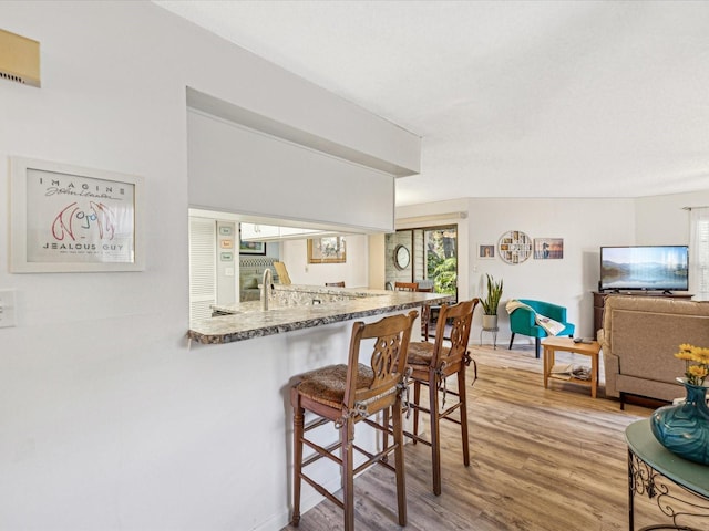 kitchen featuring a kitchen bar, kitchen peninsula, and hardwood / wood-style flooring