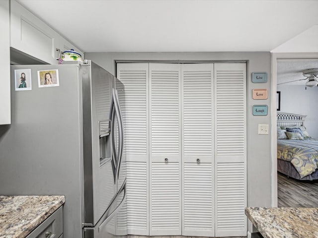 kitchen featuring white cabinets, stainless steel fridge with ice dispenser, light stone countertops, and ceiling fan