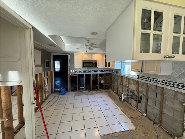 kitchen featuring ceiling fan, light tile patterned flooring, and a textured ceiling