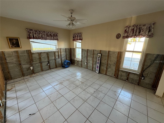 interior space with ceiling fan, a healthy amount of sunlight, and tile walls