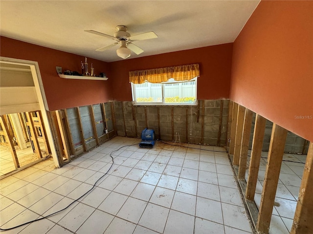 unfurnished room featuring ceiling fan and tile walls