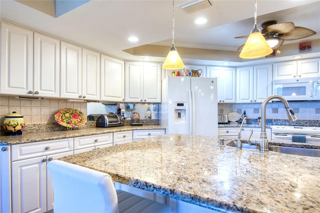 kitchen featuring pendant lighting, white cabinets, and white appliances