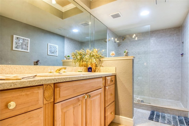 bathroom featuring tile patterned flooring, a tile shower, and vanity