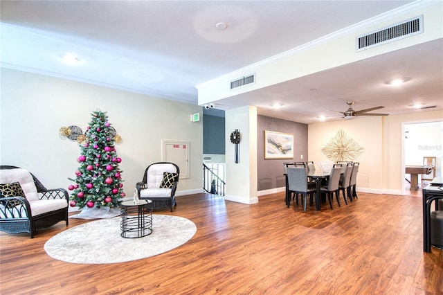 living room with crown molding, ceiling fan, and wood-type flooring